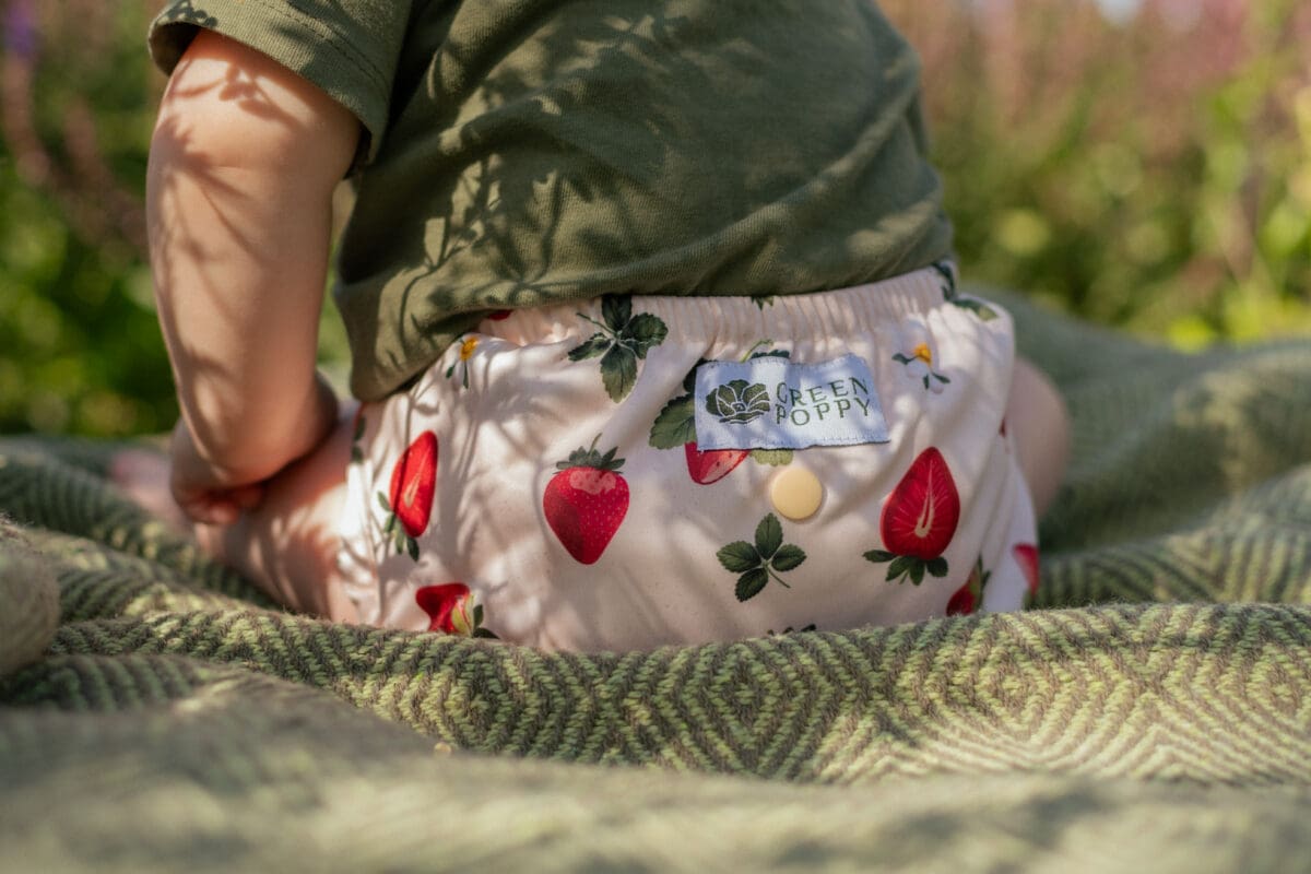 ett barn i ett pul-skal med jordgubbar på i somrig utemiljö