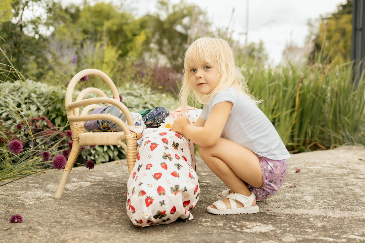 en stor pul-påse med jordgubbar på och ett barn som sitter på huk och plockar med påsen